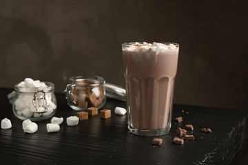 Tasty hot chocolate with milk and marshmallows in glass on table