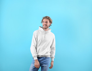 Fototapeta premium Portrait of man in hoodie sweater on color background. Space for design
