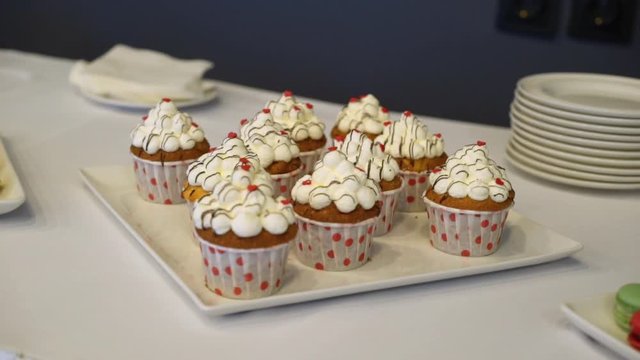 Capcakes with white cream and red berries on a white dish at buffet