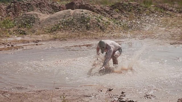 Funny guy in shorts and a gas mask running around in a puddle. Unbridled fun