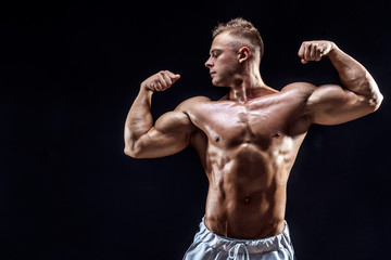Fototapeta na wymiar Handsome strong bodybuilder posing in studio on black background