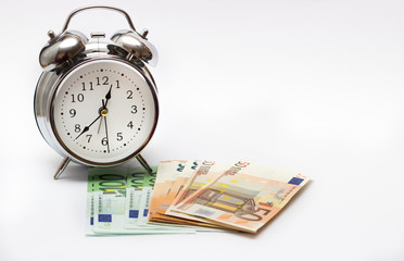 alarm clock, and European paper money, on a white background. Business concept, time is money.