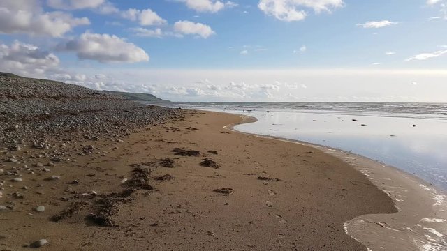 Footage of Fairbourne beach in Wales with pebbles covering the sandy beach.