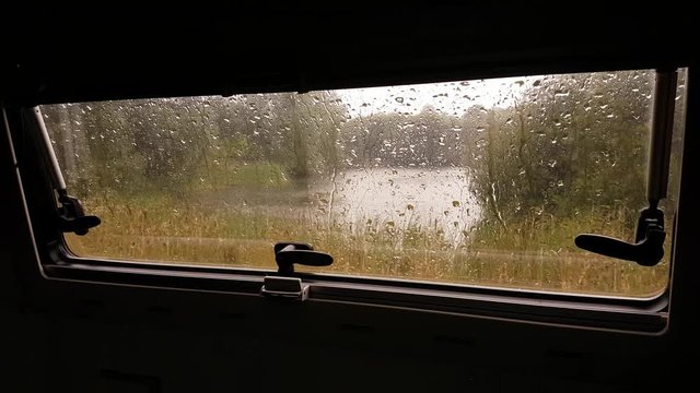 Pouring rain seen through a motorhome caravan window.
