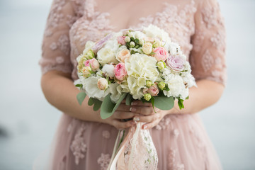 Beautiful wedding bouquet with roses and other flowers. In bride hand