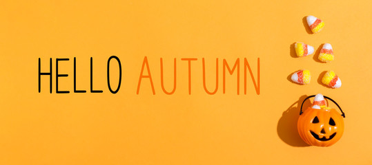 Naklejka premium Hello Autumn message with pumpkin overhead view on a solid color