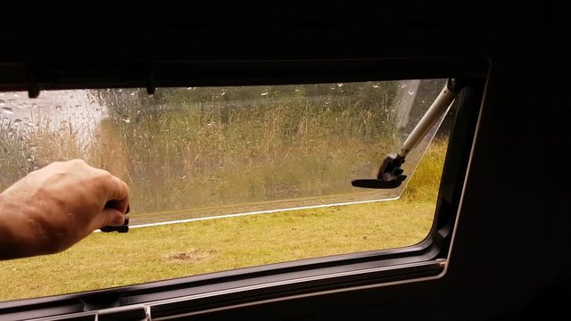 Opening a motorhome caravan window on a rainy day.