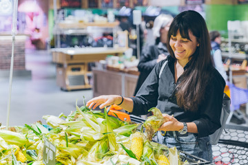 woman choosing corn in grocery shop © phpetrunina14