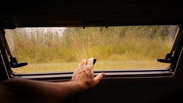 Closing a motorhome caravan window on rainy day.