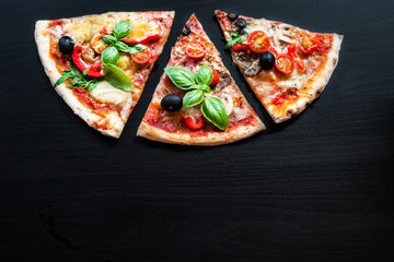 Delicious Italian pizza slice on black concrete background. Copyspace. Top view. Close up