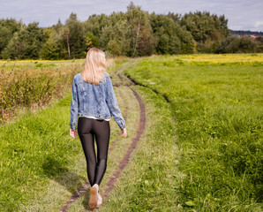 girl dressed in leggings and denim jacket walking on country road