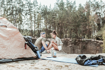 Relaxing in forest. Couple of active young backpackers relaxing in forest while listening to music and drinking tea