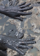 Hands smeared with black healing mud