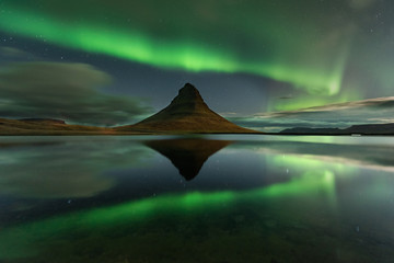 The Northern Light at the mountain Kirkjufell Iceland. Amazing landscape with green bands of Aurora Borealis. Snaefellnes, Iceland