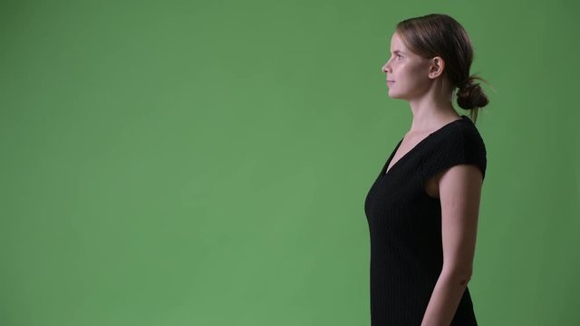 Profile view of young beautiful businesswoman against green background