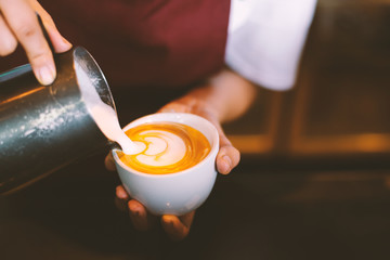 close up barista hands making latte art in cafe,copy space,warm retro tone.