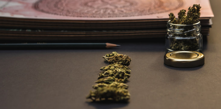 Cannabis bud lineup, stationery, joint, jar, pages on black background