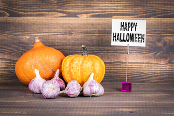 Happy Halloween, pumpkins and garlic on a wooden background