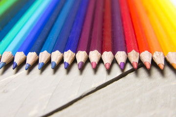 pastelli colorati disposti in linea sopra un tavolo di legno