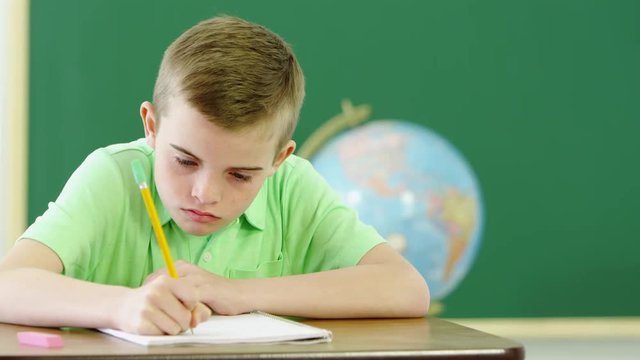 Loop of Young boy writing and taking notes