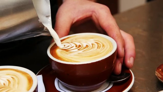 Loop of Barista creates latte art, slow motion close up