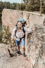 Hiker with backpack. Bearded handsome strong hiker wearing shorts and squared shirt hiking in the mountains with backpack