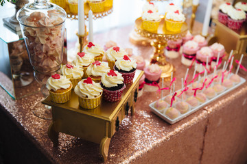 Candy bar, a table with sweets and desserts on the table. Buffet with delicious cupcakes, cake pops, biscuits, flowers.