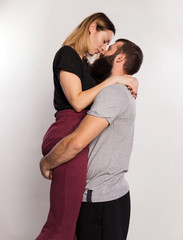 Romantic kisses. Happy young man carrying, hugging and kiss beautiful girl. Lovely couple attractive woman and handsome bearded man isolated on grey