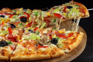 A piece of bright vegetarian pizza is separated from the whole