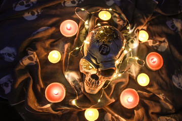 Helloween skull in the dark with a garland.Warm light and brown candles