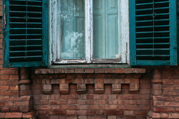 Fototapeta na wymiar Old green window with open shutters. Brick wall