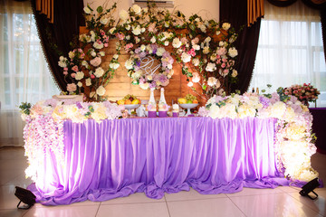 The concept of a wedding celebration, celebration of lovers, decor, flowers, fabrics. The table of the newlyweds is decorated with flowers, candles and fabrics.