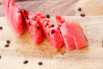 Pink watermelon on wooden board with brown seeds