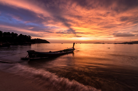 Pink sunset on a beach with silouhette of a boat in Thailand © Alexandre