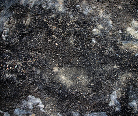 Rough dark stone surface. There are light blotches. Fragment of an old stone wall.