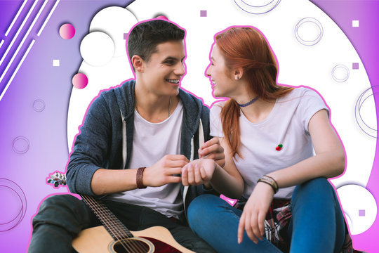 Common interests. Handsome young man smiling to his girlfriend while sitting close to her and talking about his guitar lessons