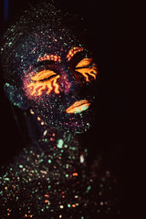 Portrait of a girl painted in fluorescent powder. Halloween concept.