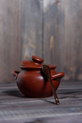 Clay pot with a spoon on a wooden table. The concept of cooking tasty and healthy food.