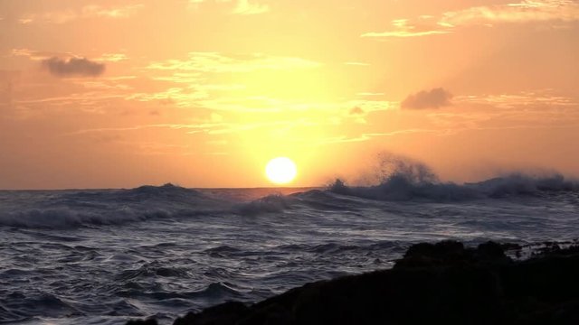 Loop of SLOW MOTION: Curly ocean waves splattering in restless sea at golden sunset