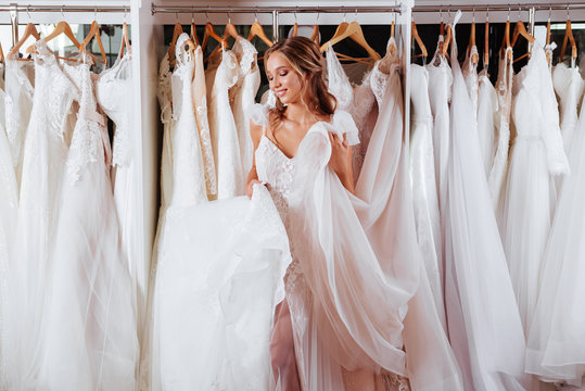 Back view of a young woman in wedding dress looking at bridal gowns