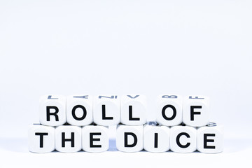 Lettered dice spelling out the phrase roll of the dice on a white background