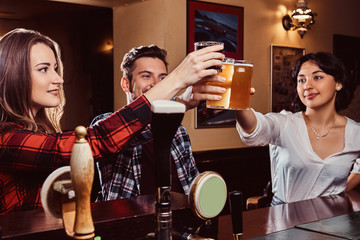 Happy multiracial friends making a toast with beer at bar or pub.