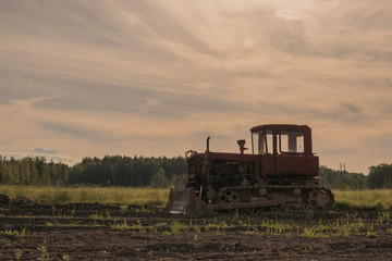 Naklejka premium Old abandoned tractor in a plowed field