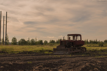 Fototapeta premium Old abandoned tractor in a plowed field