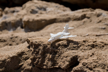 White toy plane standing on an edge of a cliff.