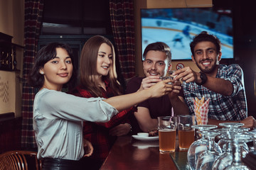 Group of happy multiracial friends making a toast with beer at bar or pub.