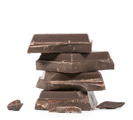 Close up of chocolate pieces stack and chocolate syrup on white background