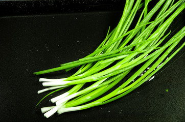 Green leek in the sink for washing on a dark background for cooking with free space