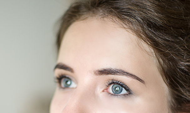 girl with blue eyes looking up, architecture of eyebrows, coloring and correction of eyebrows, registration of eyebrows, blue eyes of the girl