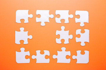 White puzzle on orange background. Missing piece. Top view